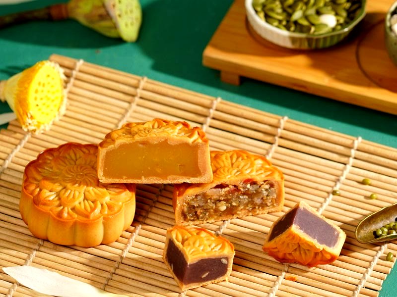 Bánh nướng Bảo Minh cắt đôi bày trên mành tre, bên cạnh là hạt sen và đậu xanh